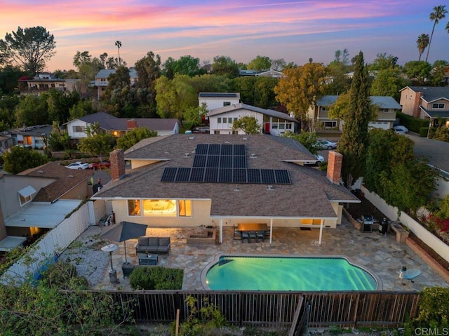 5171 College Gardens Ct, San Diego, CA 92115 - back of house at dusk with a fenced backyard, a chimney, a patio, outdoor dining space, and solar panels