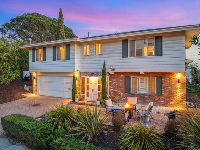 5171 College Gardens Ct, San Diego, CA 92115 - view of front of house featuring decorative driveway, a fire pit, brick siding, and a garage