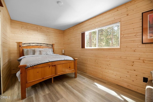 bedroom featuring wooden walls and wood finished floors