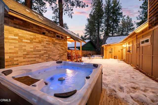 patio terrace at dusk featuring a hot tub and fence