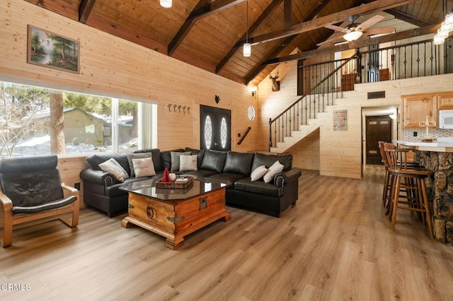living area with light wood-type flooring, beamed ceiling, stairway, wooden walls, and wooden ceiling