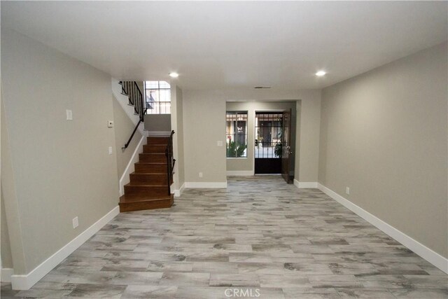 interior space featuring light wood-style floors, baseboards, and stairway