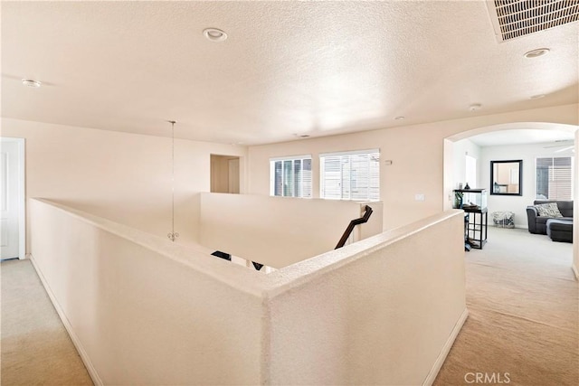 3070 Sand Pine Trl, Hemet, CA 92545 - hallway with visible vents, arched walkways, a textured ceiling, light carpet, and an upstairs landing