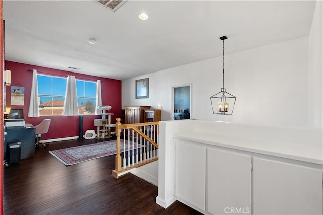 interior space featuring visible vents, baseboards, dark wood finished floors, an upstairs landing, and an inviting chandelier
