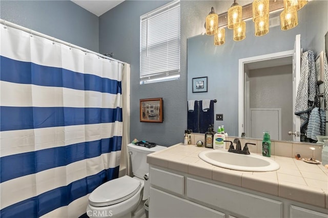 full bathroom featuring curtained shower, toilet, vanity, and a textured wall