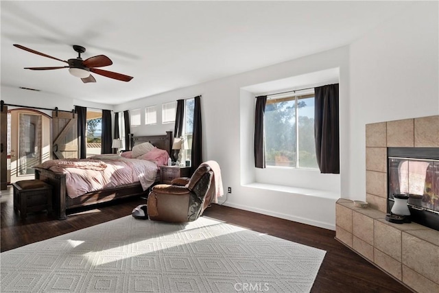 bedroom featuring dark wood finished floors, visible vents, multiple windows, and a tiled fireplace