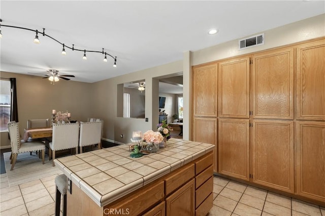 kitchen with tile counters, light tile patterned floors, visible vents, and ceiling fan