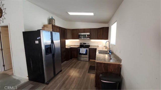 kitchen with dark wood-style flooring, a sink, stainless steel appliances, vaulted ceiling, and dark brown cabinetry