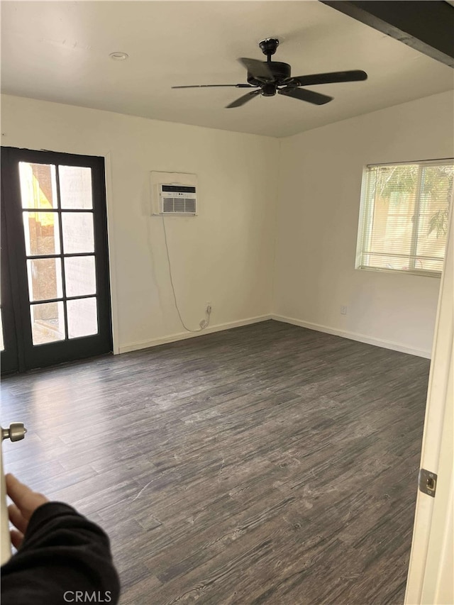 unfurnished room with ceiling fan, baseboards, dark wood finished floors, and a wall mounted AC
