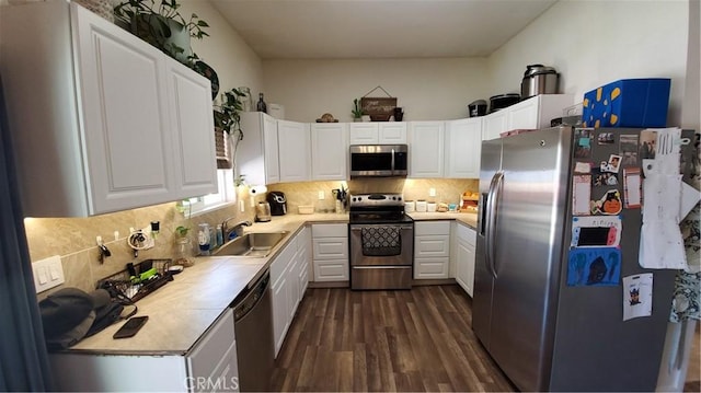 kitchen with dark wood-style flooring, a sink, stainless steel appliances, white cabinets, and tasteful backsplash