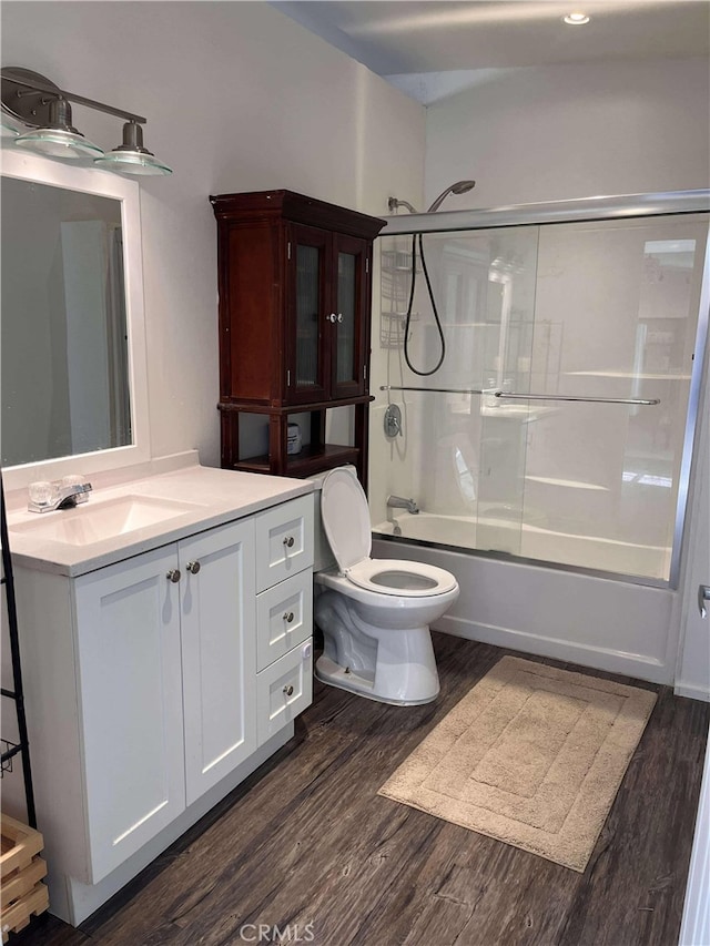 bathroom featuring combined bath / shower with glass door, toilet, wood finished floors, and vanity
