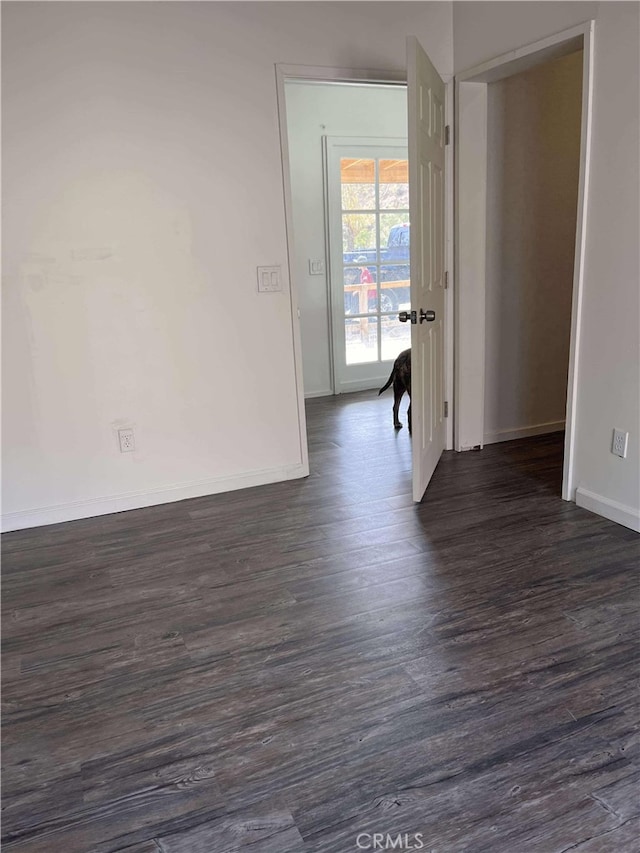spare room featuring dark wood-style floors and baseboards
