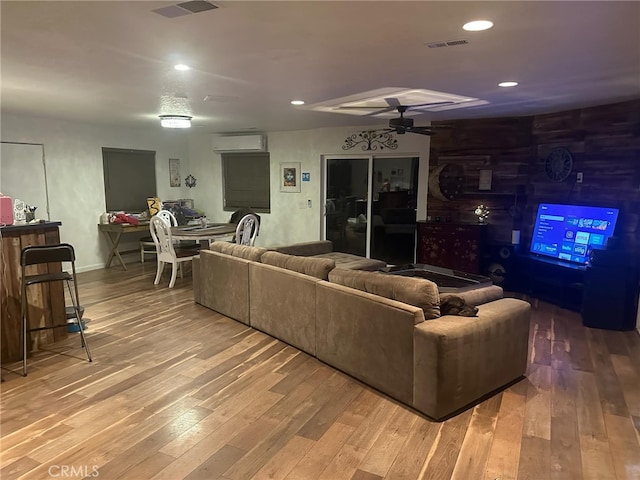living area with visible vents, an AC wall unit, ceiling fan, and hardwood / wood-style flooring