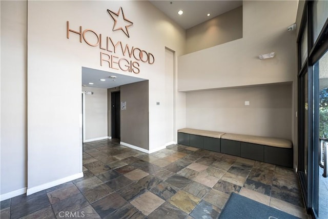 7320 Hawthorn Ave Unit 111, Los Angeles, CA 90046 - unfurnished room featuring stone tile flooring, baseboards, a high ceiling, and recessed lighting