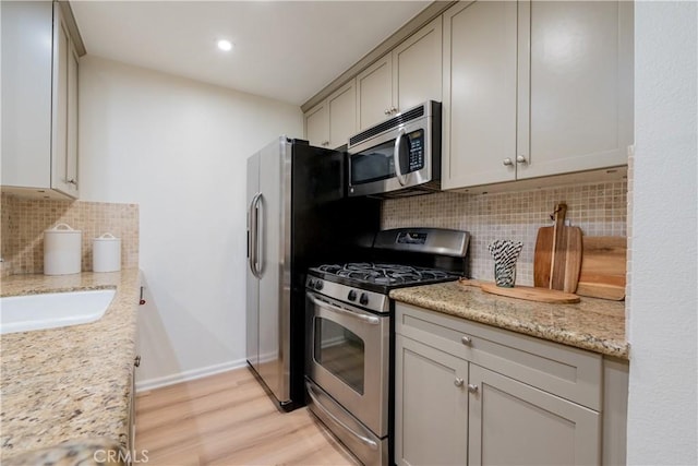 7320 Hawthorn Ave Unit 111, Los Angeles, CA 90046 - kitchen featuring stainless steel appliances, tasteful backsplash, light wood-style floors, baseboards, and light stone counters