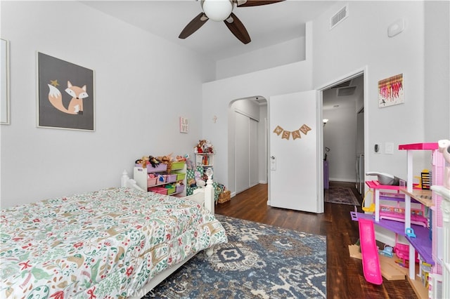 bedroom featuring ceiling fan, visible vents, arched walkways, and wood finished floors