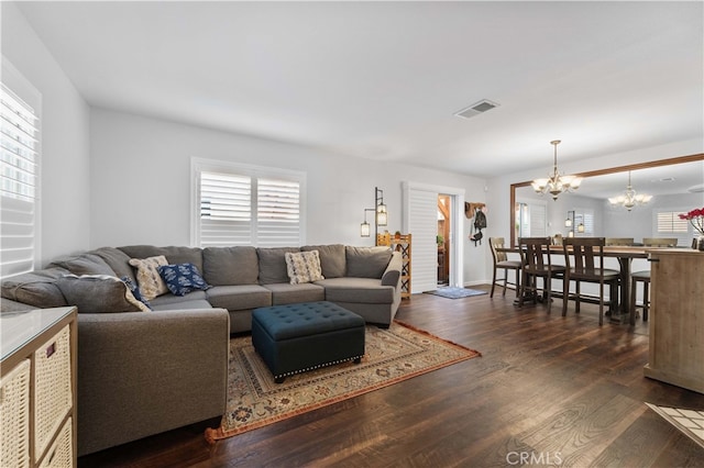 living room with visible vents, an inviting chandelier, and wood finished floors