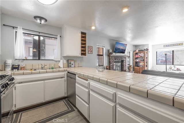 723 Summit Blvd, Big Bear Lake, CA 92315 - kitchen with a fireplace, a textured ceiling, white cabinetry, appliances with stainless steel finishes, and open floor plan