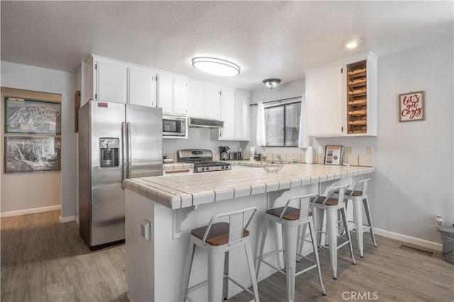 723 Summit Blvd, Big Bear Lake, CA 92315 - kitchen featuring baseboards, a peninsula, under cabinet range hood, stainless steel appliances, and light wood finished floors