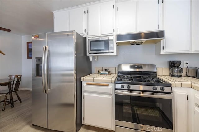 723 Summit Blvd, Big Bear Lake, CA 92315 - kitchen featuring white cabinetry, appliances with stainless steel finishes, tile countertops, and under cabinet range hood