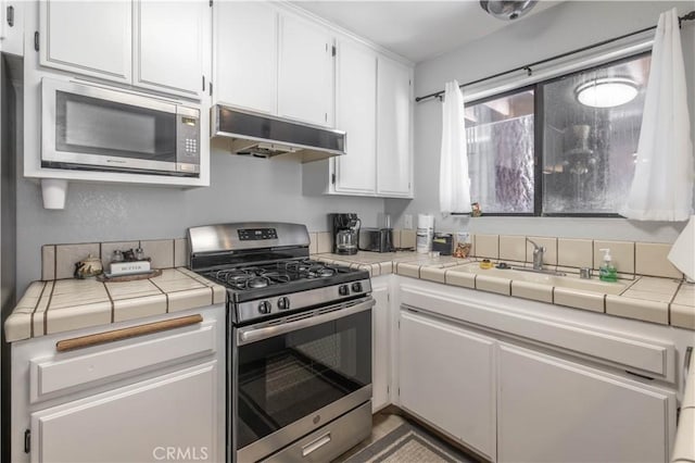 723 Summit Blvd, Big Bear Lake, CA 92315 - kitchen with tile countertops, white cabinetry, appliances with stainless steel finishes, under cabinet range hood, and a sink