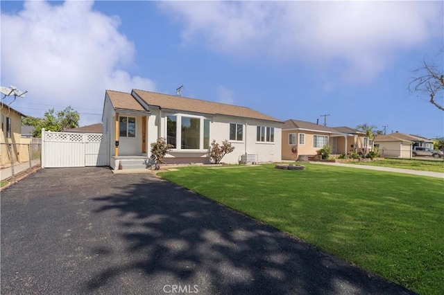 view of front of property with a front yard, fence, driveway, and stucco siding