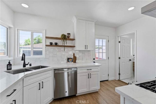kitchen with light wood-style flooring, light stone countertops, decorative backsplash, stainless steel dishwasher, and a sink