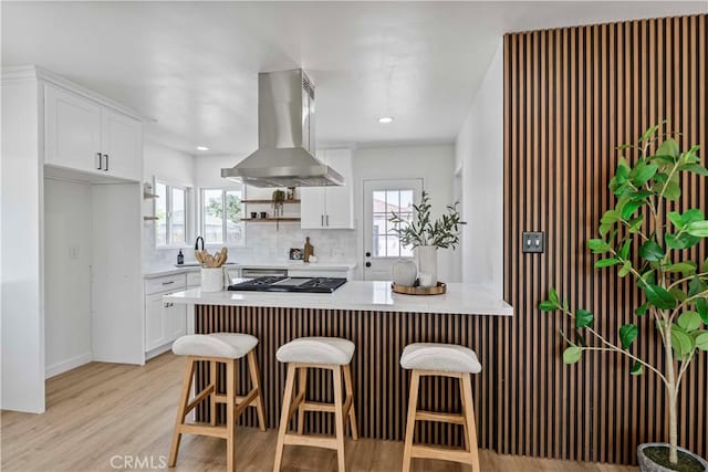 kitchen featuring island range hood, light countertops, decorative backsplash, and white cabinetry
