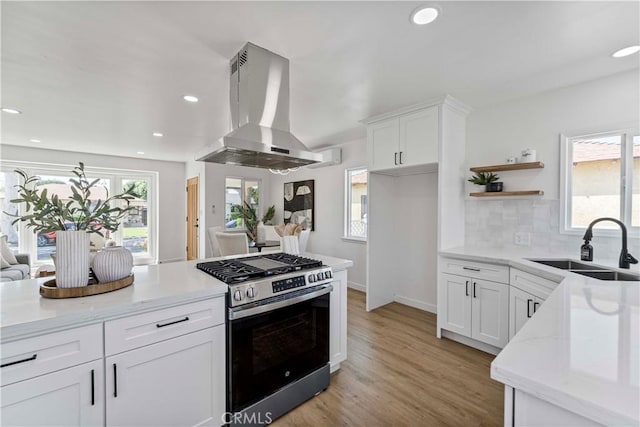 kitchen featuring open shelves, wall chimney exhaust hood, a sink, white cabinetry, and stainless steel gas stove