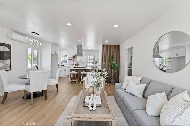 living room with light wood-type flooring, a wall unit AC, and recessed lighting