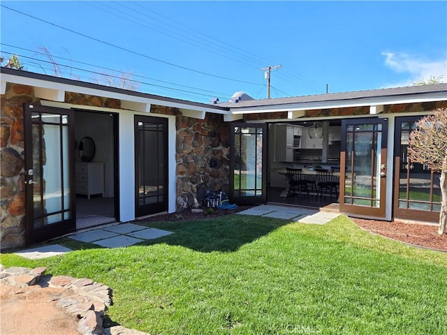 3317 Lees Ave, Long Beach, CA 90808 - rear view of house with stone siding, a yard, and a sunroom