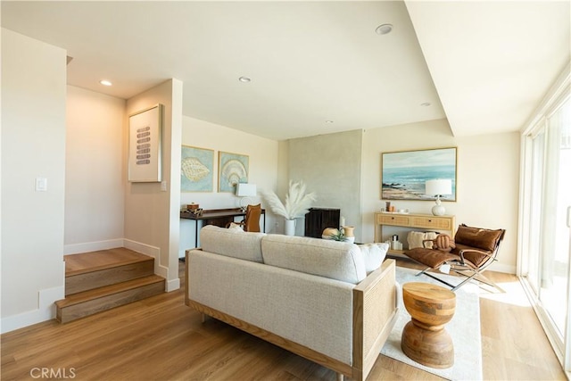 living area featuring light wood-style flooring, baseboards, stairway, and recessed lighting