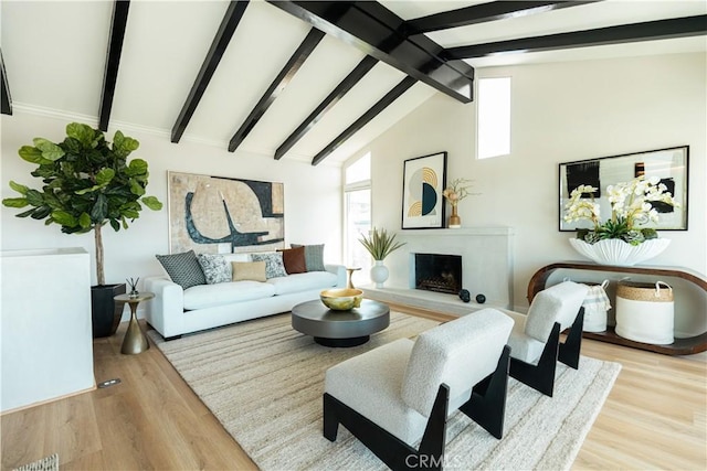 living area with lofted ceiling with beams, a fireplace with raised hearth, and wood finished floors