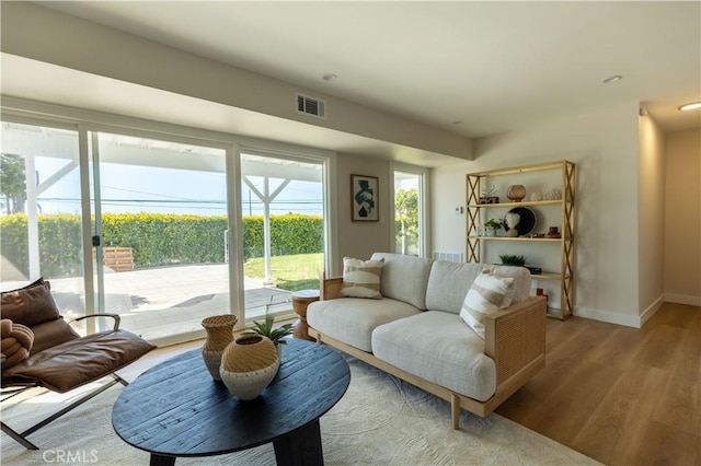 living room featuring baseboards, visible vents, and wood finished floors