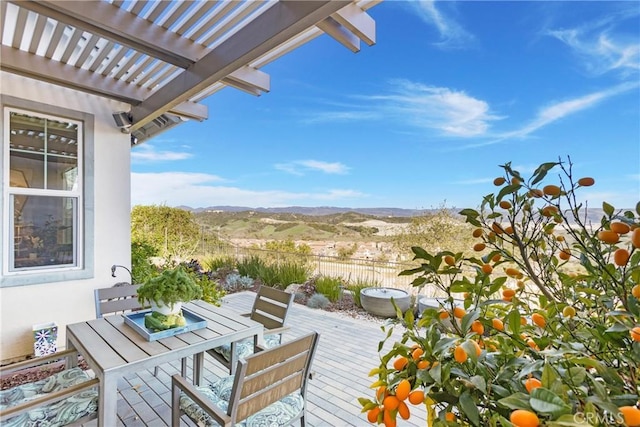 wooden terrace featuring a mountain view, fence, outdoor dining space, and a pergola