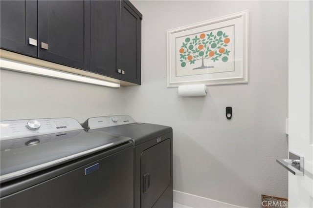 clothes washing area featuring washing machine and dryer, baseboards, and cabinet space