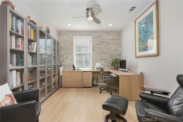 office with light wood-type flooring, visible vents, and a ceiling fan