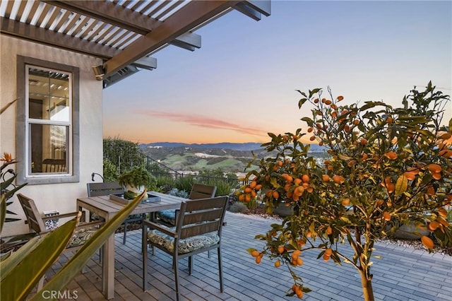 deck featuring a pergola, outdoor dining space, and a mountain view