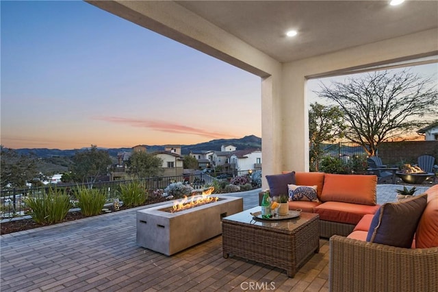 patio terrace at dusk featuring fence and an outdoor living space with a fire pit
