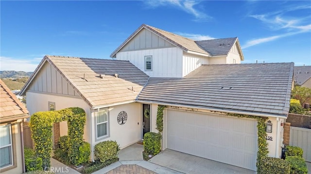 view of front of house featuring concrete driveway, a tiled roof, board and batten siding, an attached garage, and stucco siding