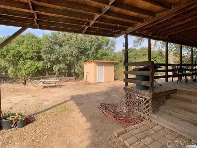 view of yard featuring a wooden deck, a storage shed, and an outdoor structure