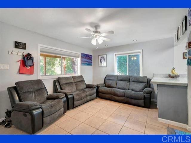 living room with light tile patterned floors, a healthy amount of sunlight, and ceiling fan