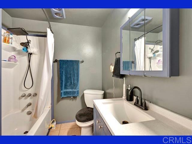 full bathroom featuring shower / bath combo with shower curtain, toilet, vanity, and tile patterned flooring