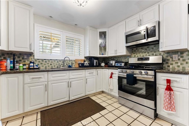 kitchen featuring white cabinetry, appliances with stainless steel finishes, decorative backsplash, and a sink