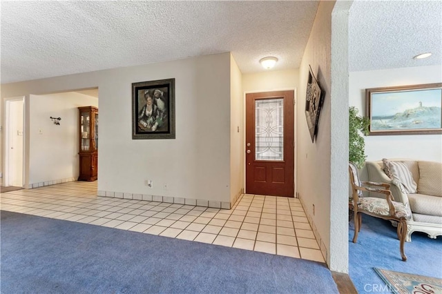 entrance foyer with light tile patterned floors, a textured ceiling, and light colored carpet