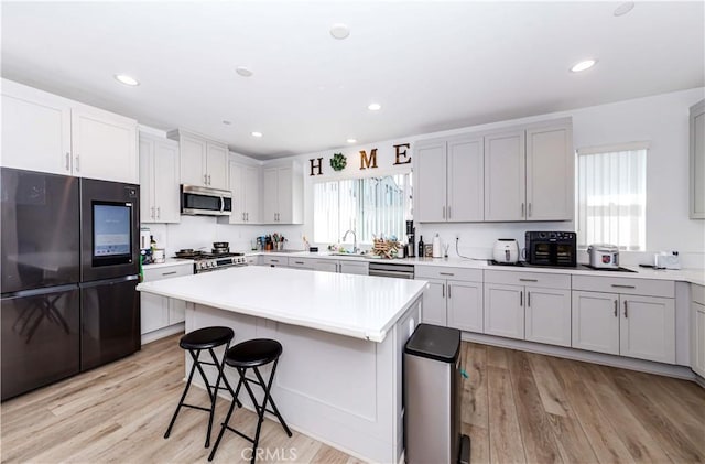 14161 Olivia Ct, La Mirada, CA 90638 - kitchen featuring light wood finished floors, a kitchen breakfast bar, light countertops, a kitchen island, and appliances with stainless steel finishes
