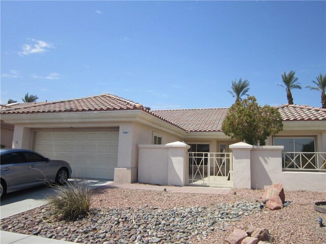 mediterranean / spanish home featuring a tiled roof, stucco siding, and an attached garage