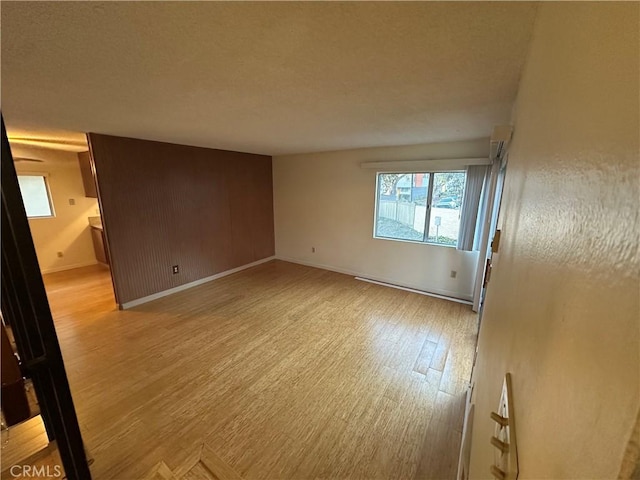 unfurnished room with baseboard heating, baseboards, and light wood-type flooring