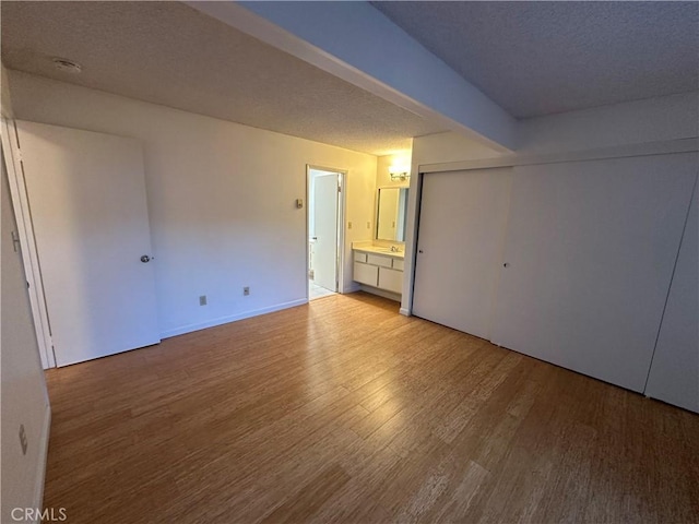 empty room with baseboards, light wood-style floors, and a textured ceiling