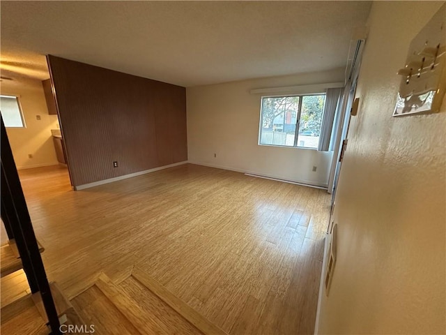 spare room featuring a baseboard heating unit, light wood finished floors, and baseboards